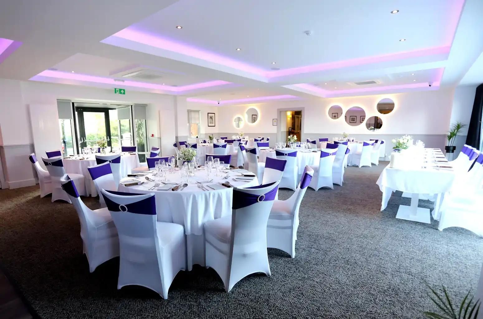 The function suite at The Balgarth Pines laid out for a wedding, bifold doors open to the garden and a long top table on the right