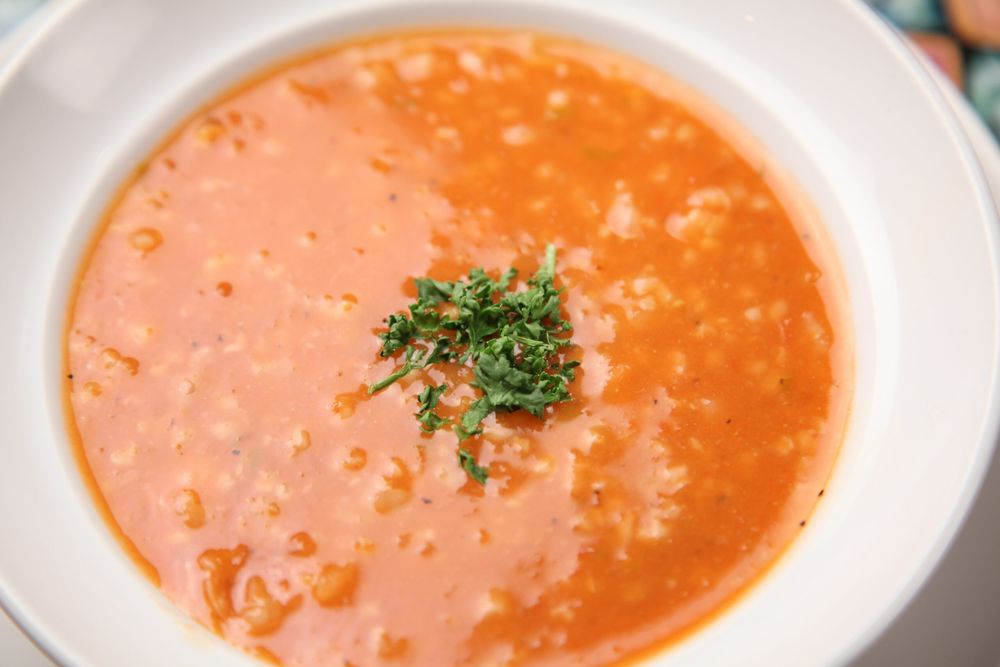 A bowl of homemade soup of the day, garnished with herbs