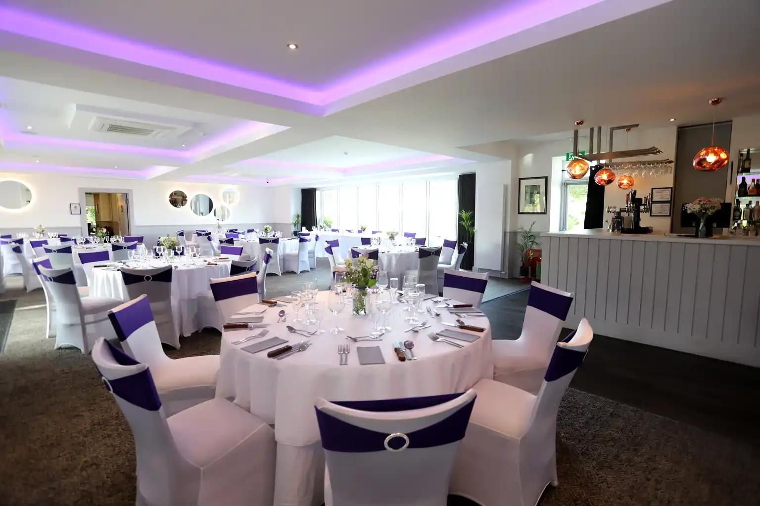 The function suite at The Balgarth Pines laid out with dressed round tables, the bar with its copper pendant lights on the right